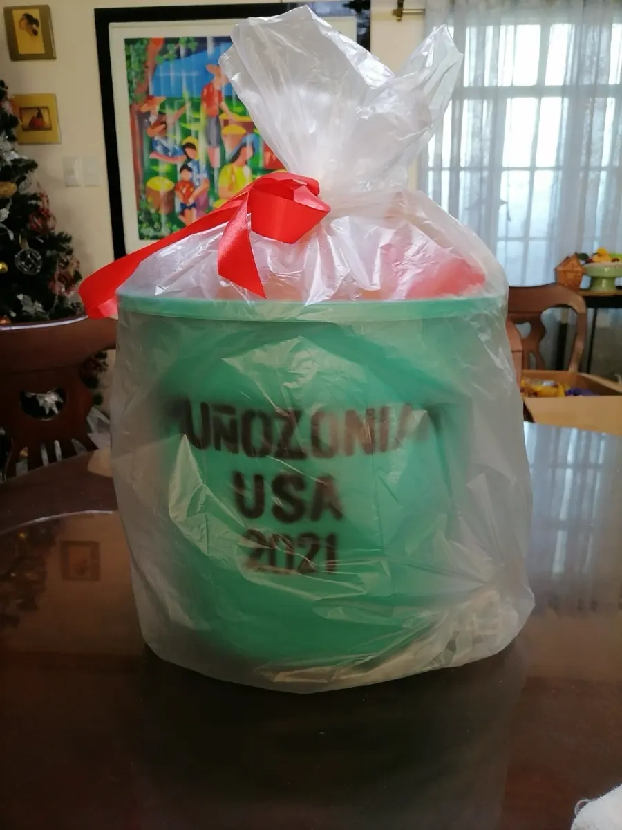 A Noche Buena basket in a green bucket lettered Muñozonian USA 2021, wrapped in plastic with a red ribbon.