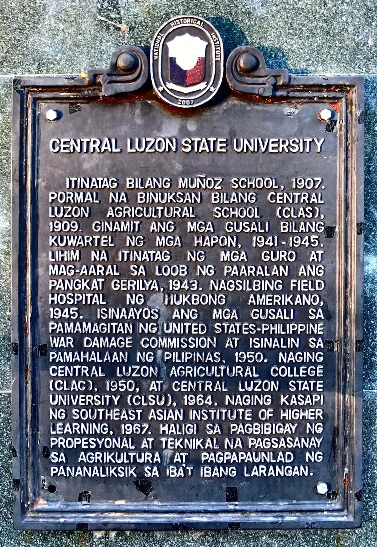 The National Historical Commission marker for Central Luzon State University, written in Filipino.